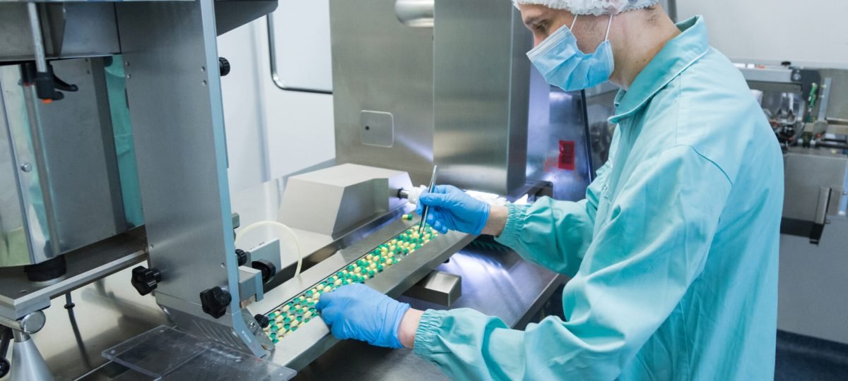 Pharmaceutical technician in sterile environment working on production of pills at pharmacy factory